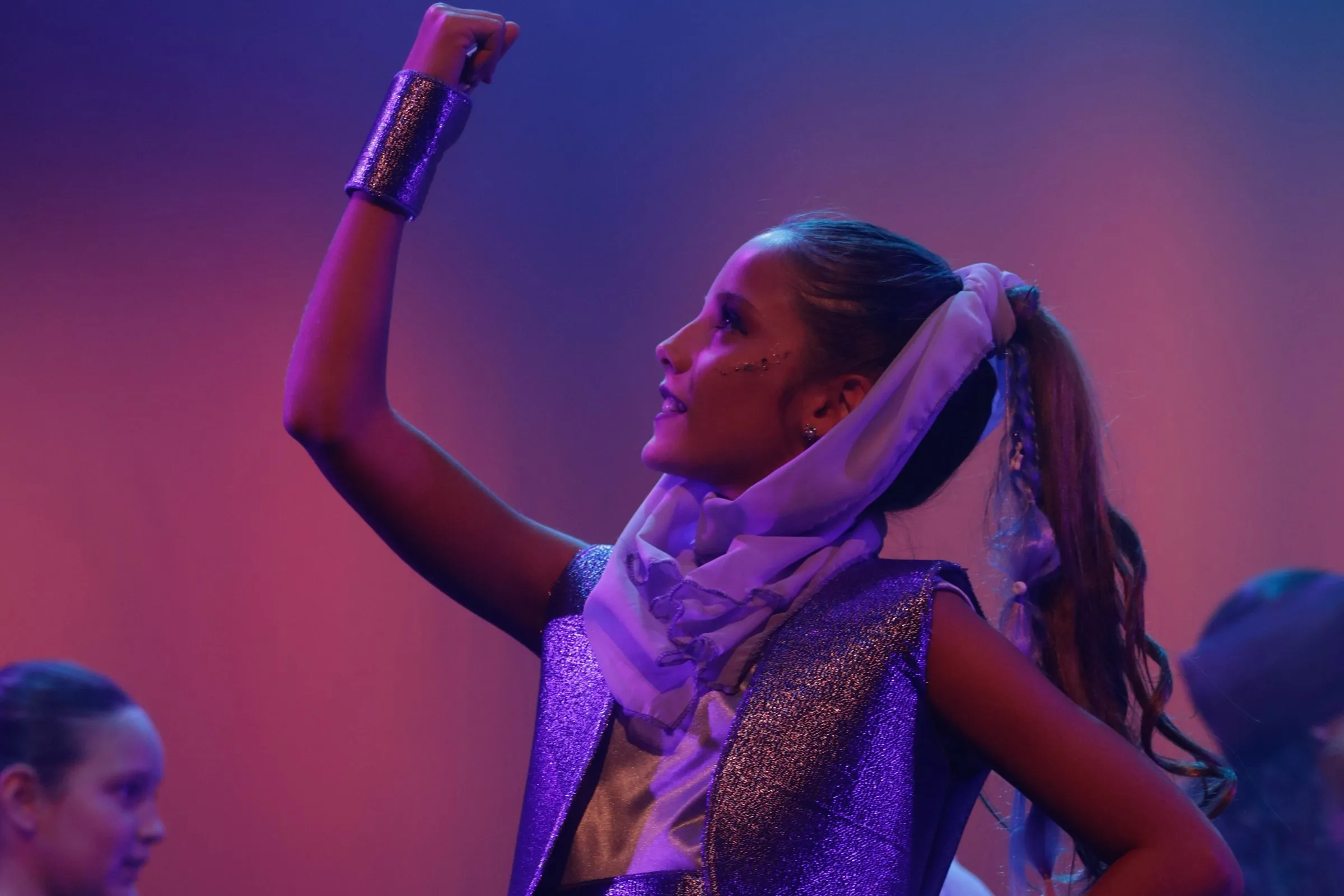 Una alumna canta como solista en Arabian Nights, iluminada por las luces del escenario