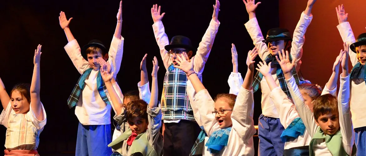 Elenco de un musical del Drama Club en escena, con vestuario de época
