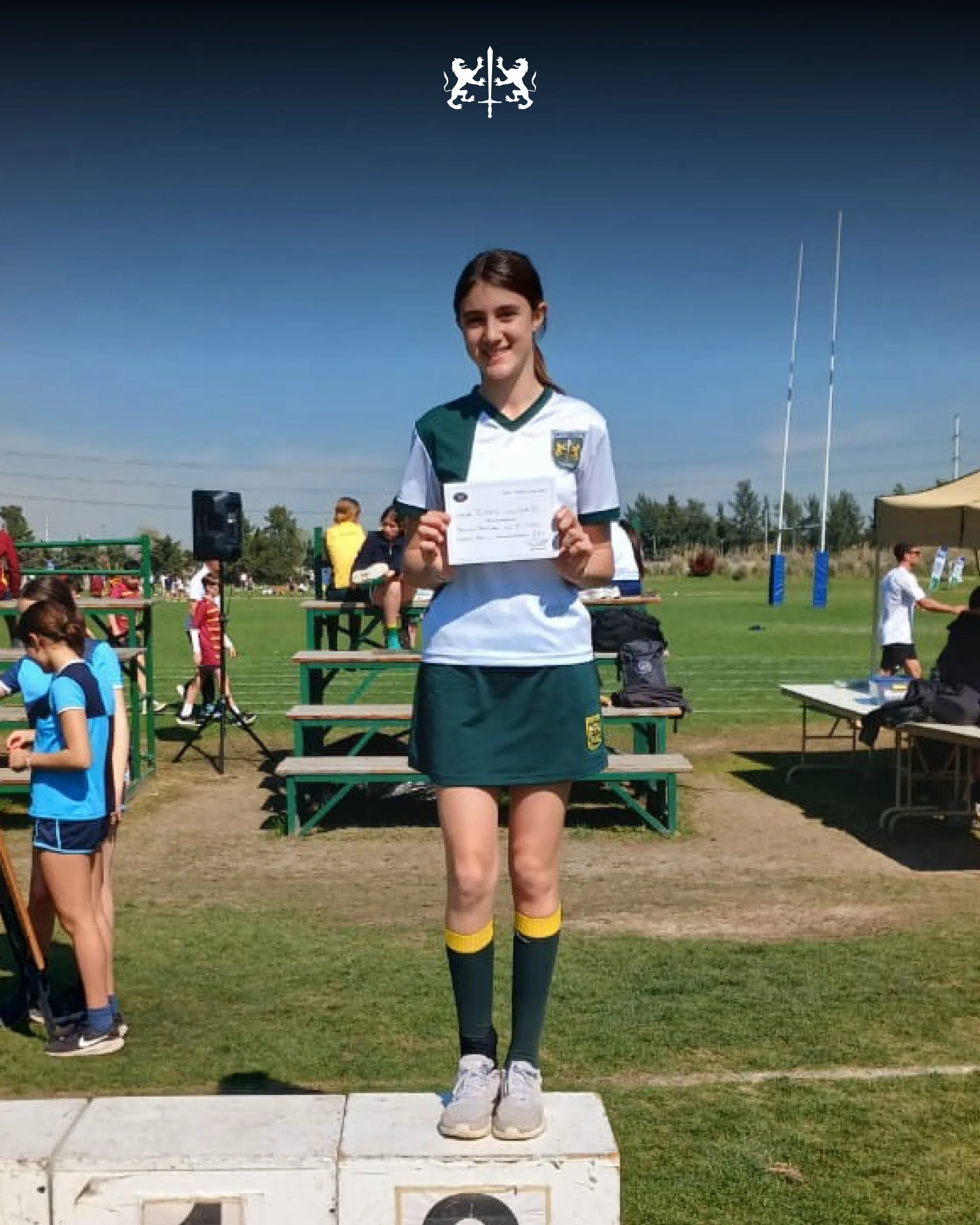Una alumna con su medalla en el podio de la competencia de atletismo de la ADE
