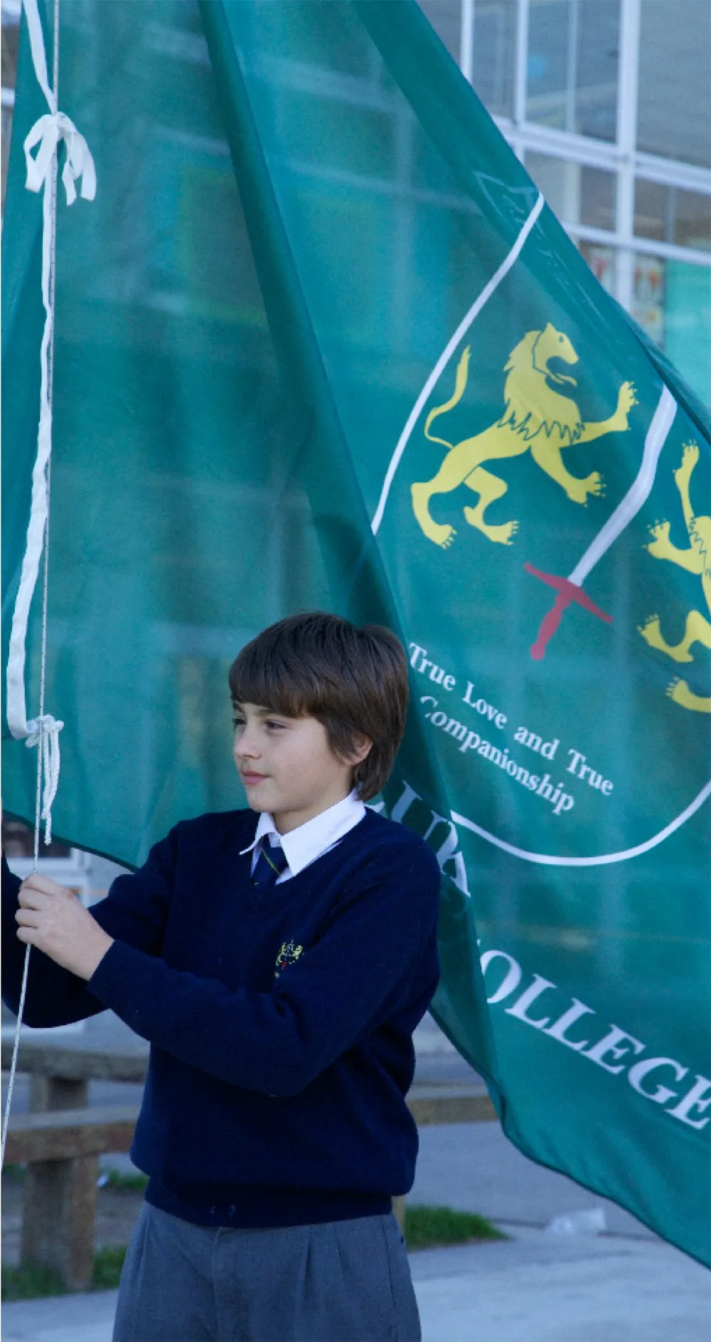 La bandera del colegio, con el escudo y el lema, izada por un alumno