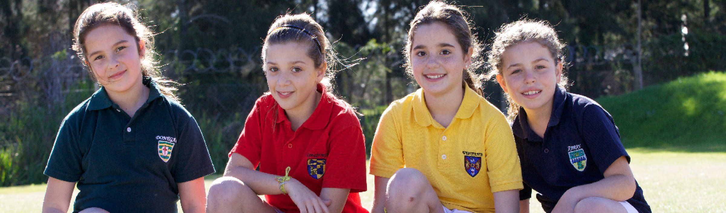 Chicas con las remeras roja y amarilla de sus Houses, sentadas en el campo