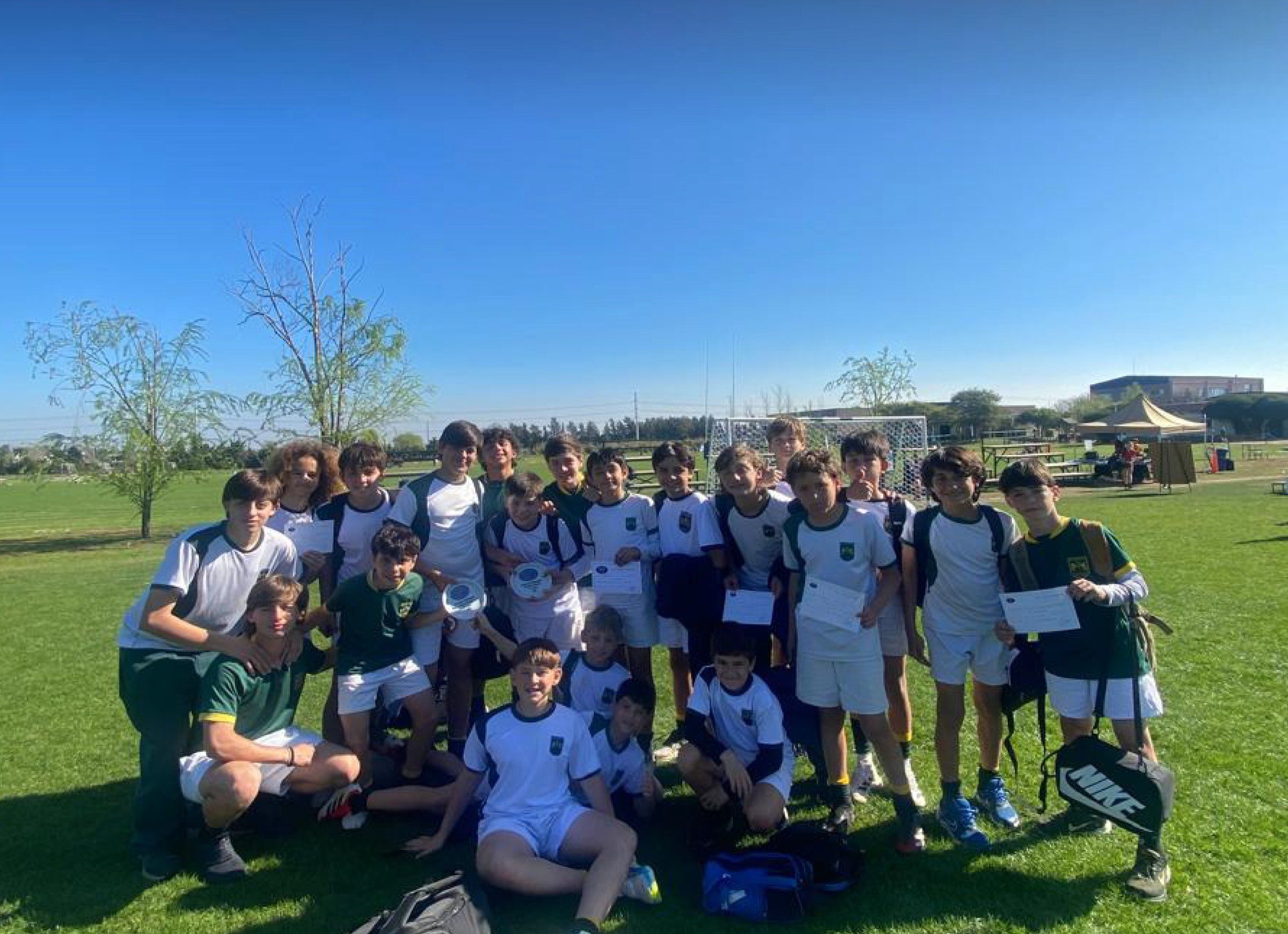Alumnos de Secundaria sentados en el césped del campo de deportes, un día de sol