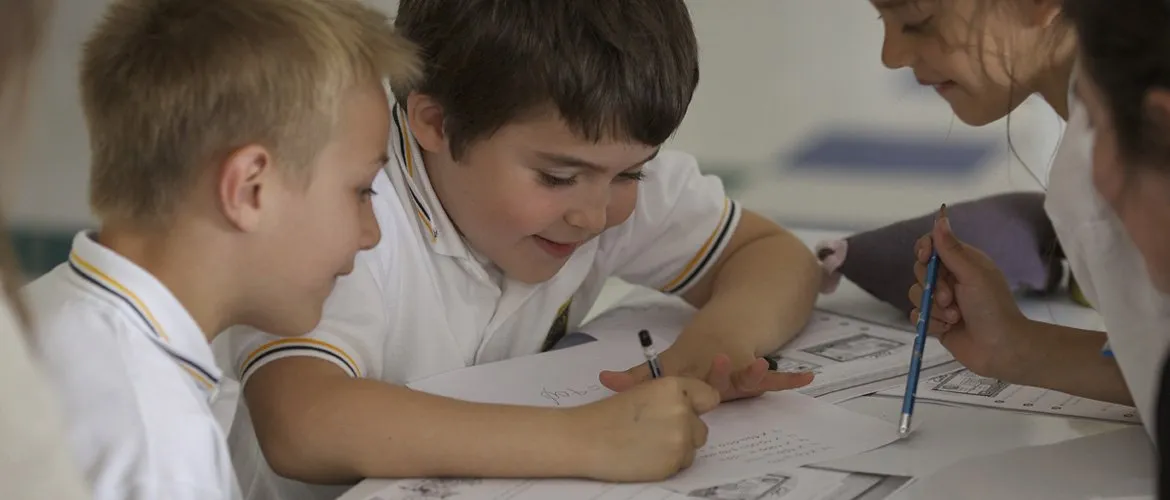 Dos alumnos de Primaria escriben y dibujan juntos en el aula