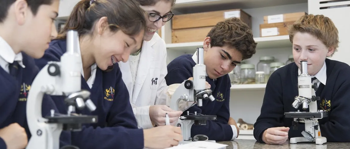Alumnas de Primaria observan por el microscopio en el laboratorio de ciencias