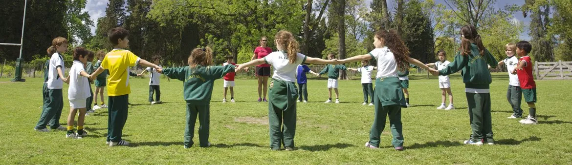 Chicos de Primaria forman una ronda tomados de la mano en el campo