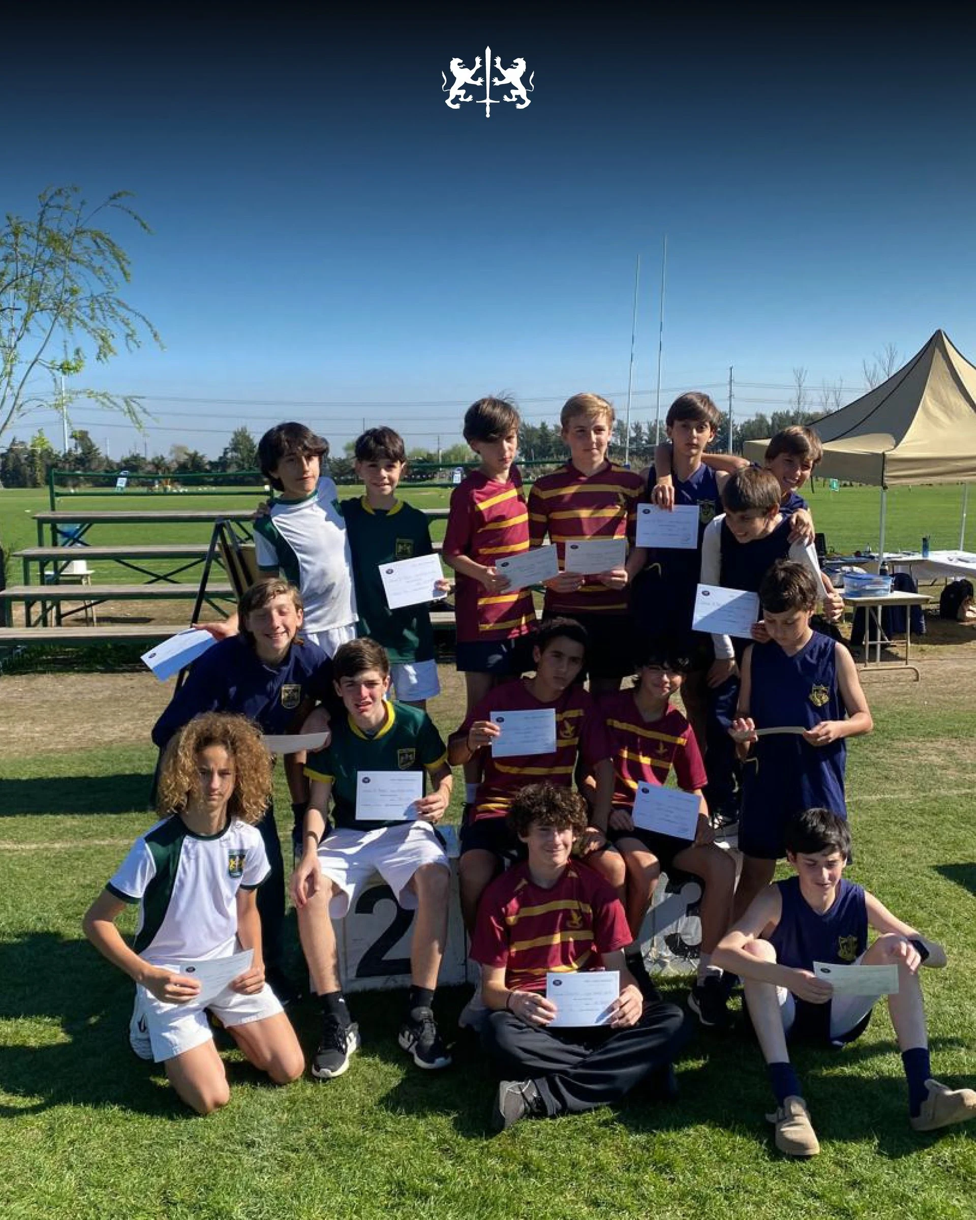 Grupo de alumnos de Secundaria con sus certificados en el campo de deportes, un día de sol
