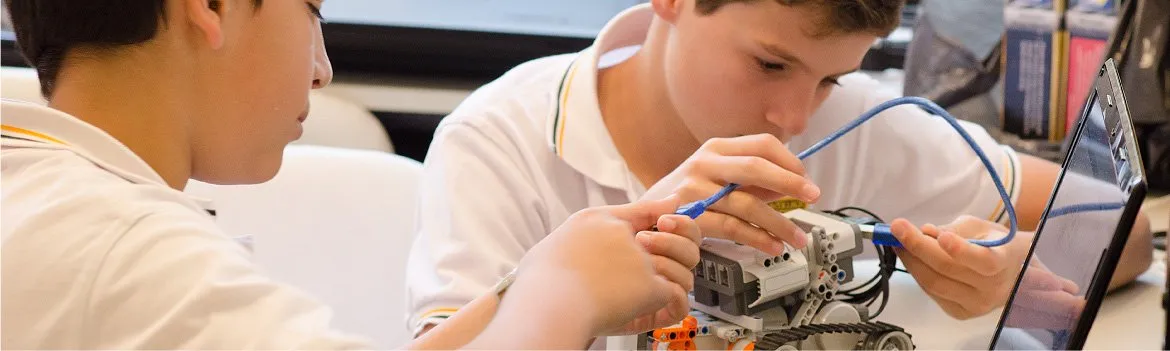 Dos alumnos arman y conectan un robot en un taller